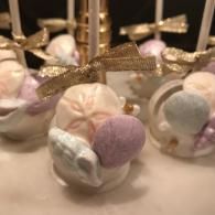 Pastel macarons topped with gold ribbon on a dessert table