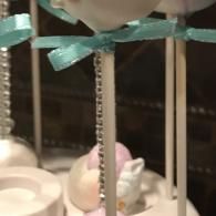 Carousel-style display of pastel rabbit figurines with mint ribbons on striped poles