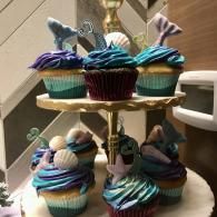 Tiered stand holding decorated cupcakes with blue and purple frosting
