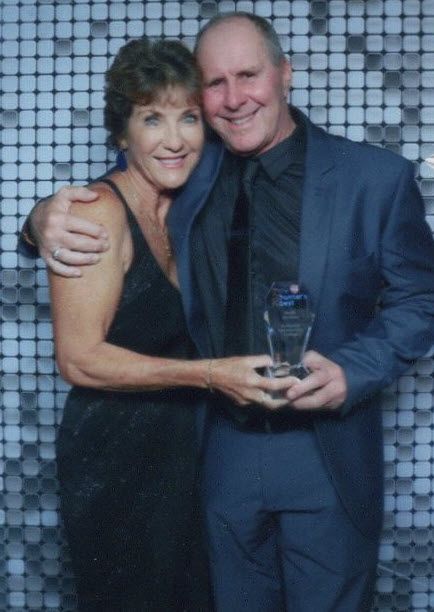 A Man and Woman are Posing for a Picture while they are Holding a Trophy