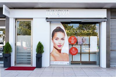 Fachada de una clínica de estética con un gran póster de una mujer en el escaparate y puertas de entrada de cristal.