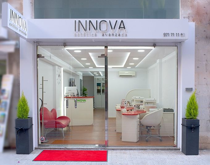Local comercial INNOVA con entrada de cristal, alfombra roja y modernas sillas de oficina en el interior.