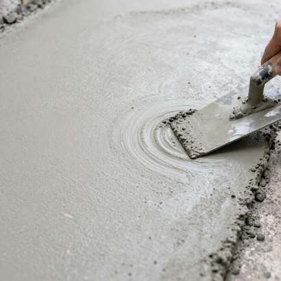 A trowel smoothing wet concrete on a floor, with circular trowel marks visible.