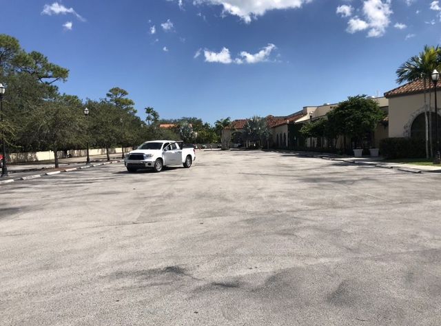 Empty parking lot with a white pickup truck under a bright blue sky
