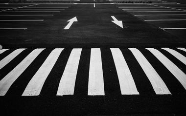 Black-and-white road crossing with zebra stripes and two arrows pointing forward