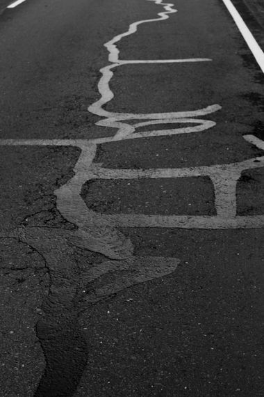 Cracked asphalt road with large white painted letters and lane markings on the right edge