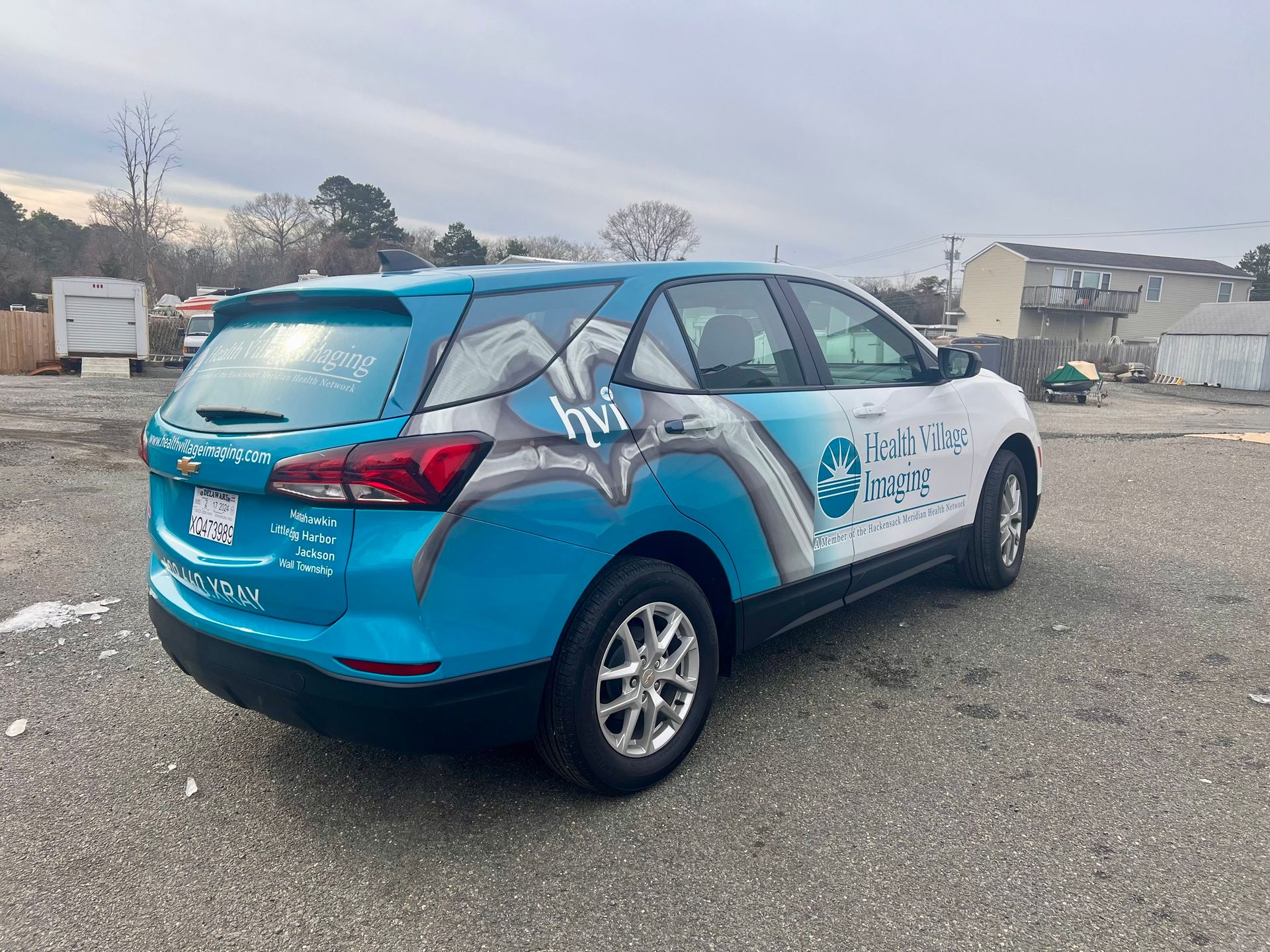 Blue and white wrapped SUV parked in an open lot under an overcast sky