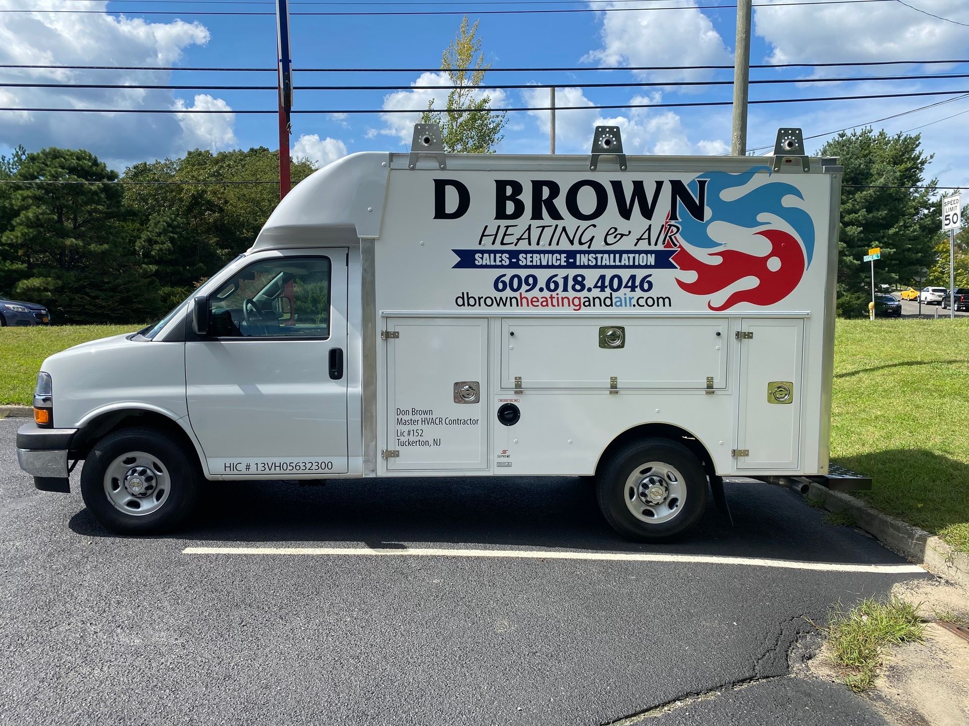 White D. Brown plumbing service van parked outdoors under a blue sky.