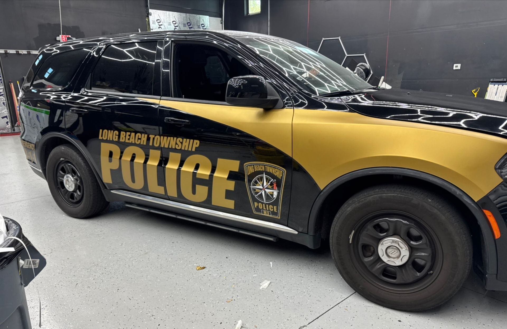 Black-and-gold police car inside a garage, labeled “POLICE” and “Lima Area Transit System”