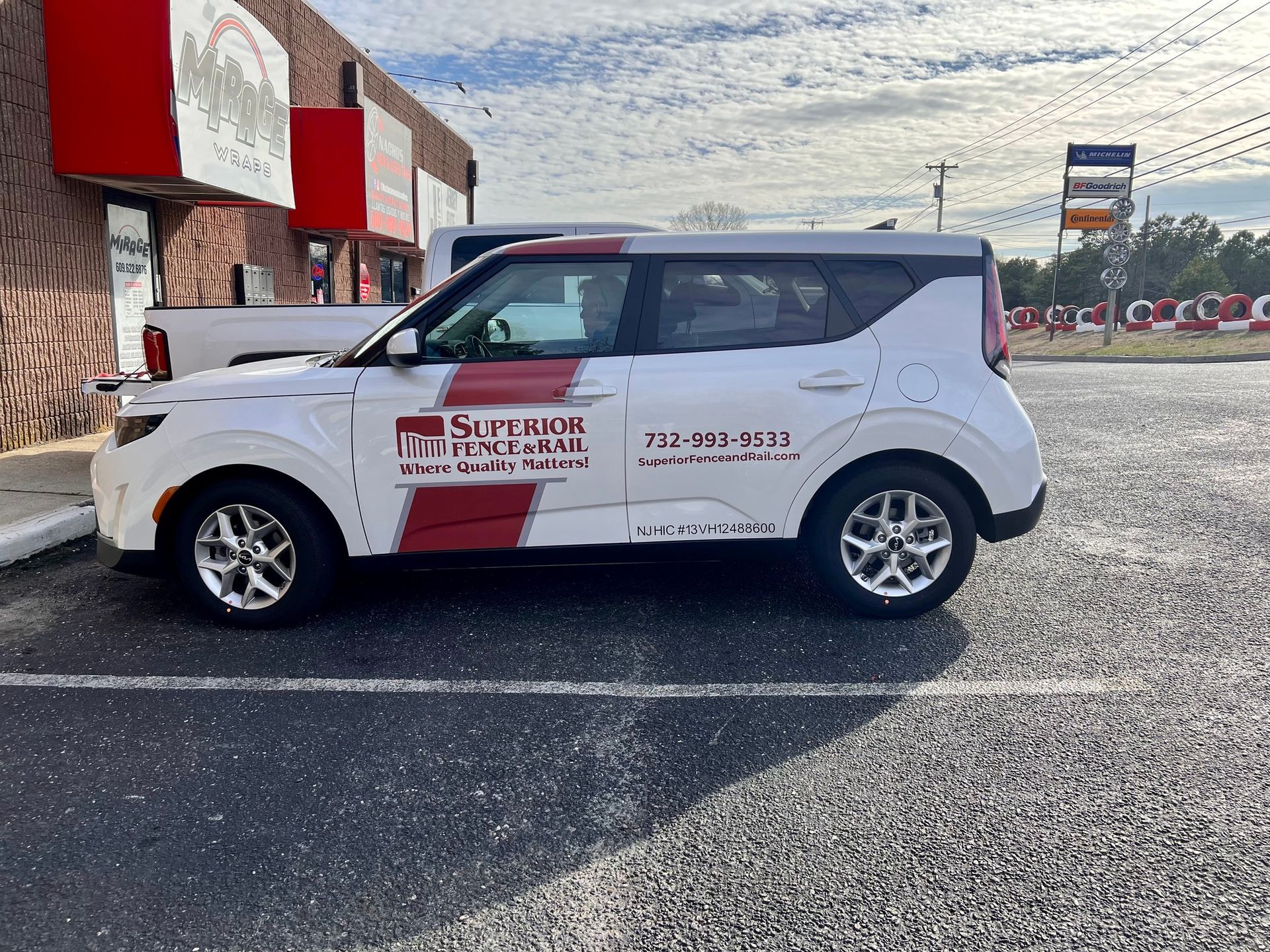 White advertising SUV parked outside a building with red awnings and a rocky hillside backdrop