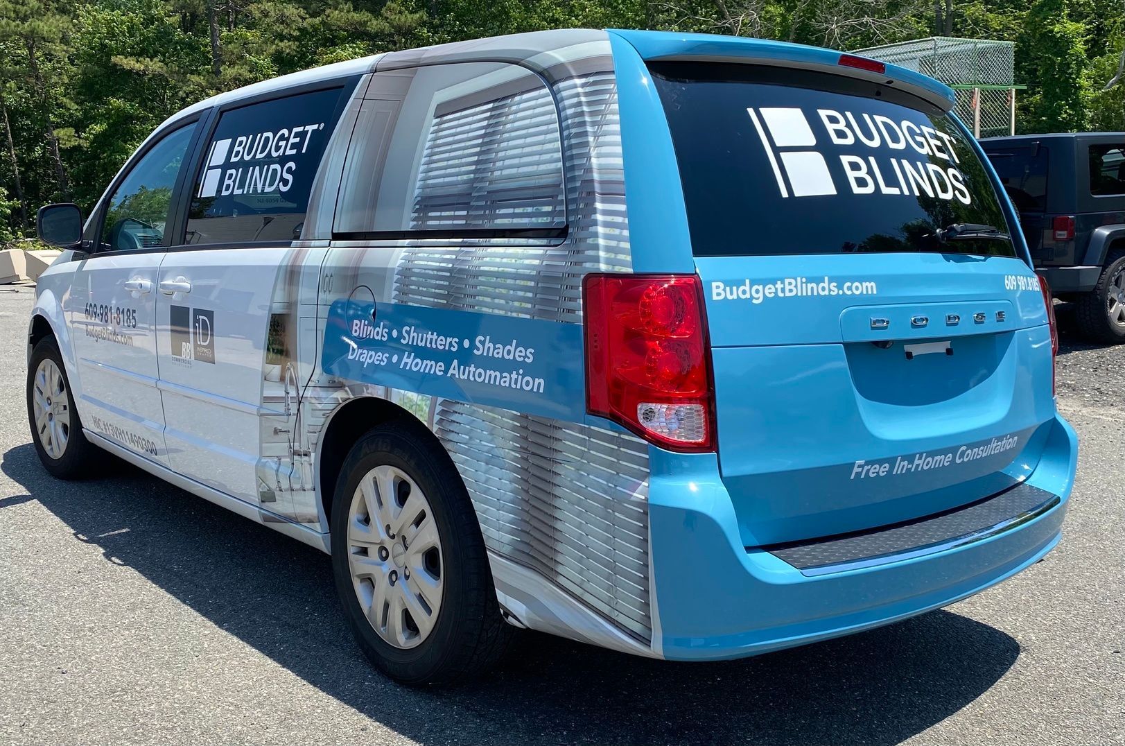 Blue and white minivan with “BUMP BLINDS” branding parked outdoors on a sunny street.