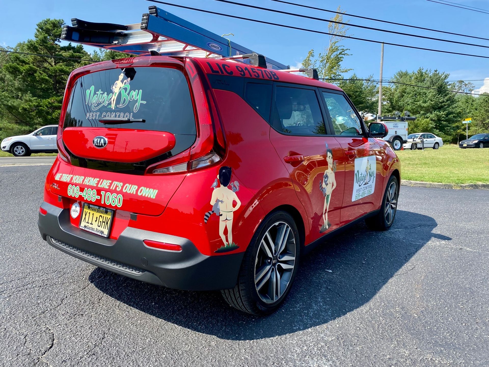 Red event van with roof rack parked in a sunny lot, with colorful logos and graphics on the sides