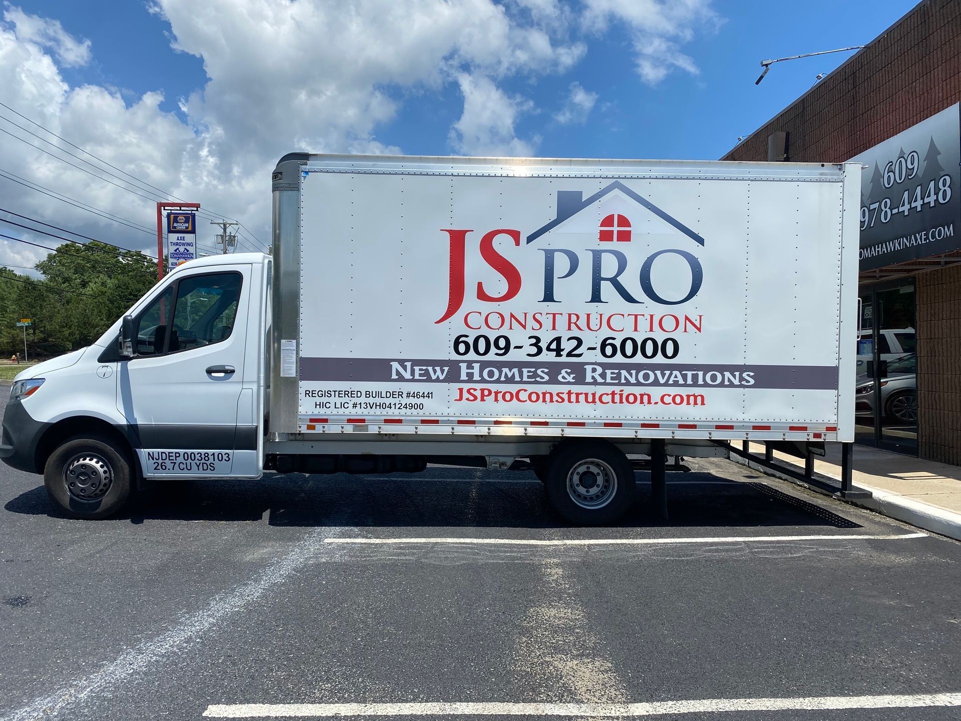 White JS Pro Construction truck with company logo and phone number parked outdoors under a blue sky