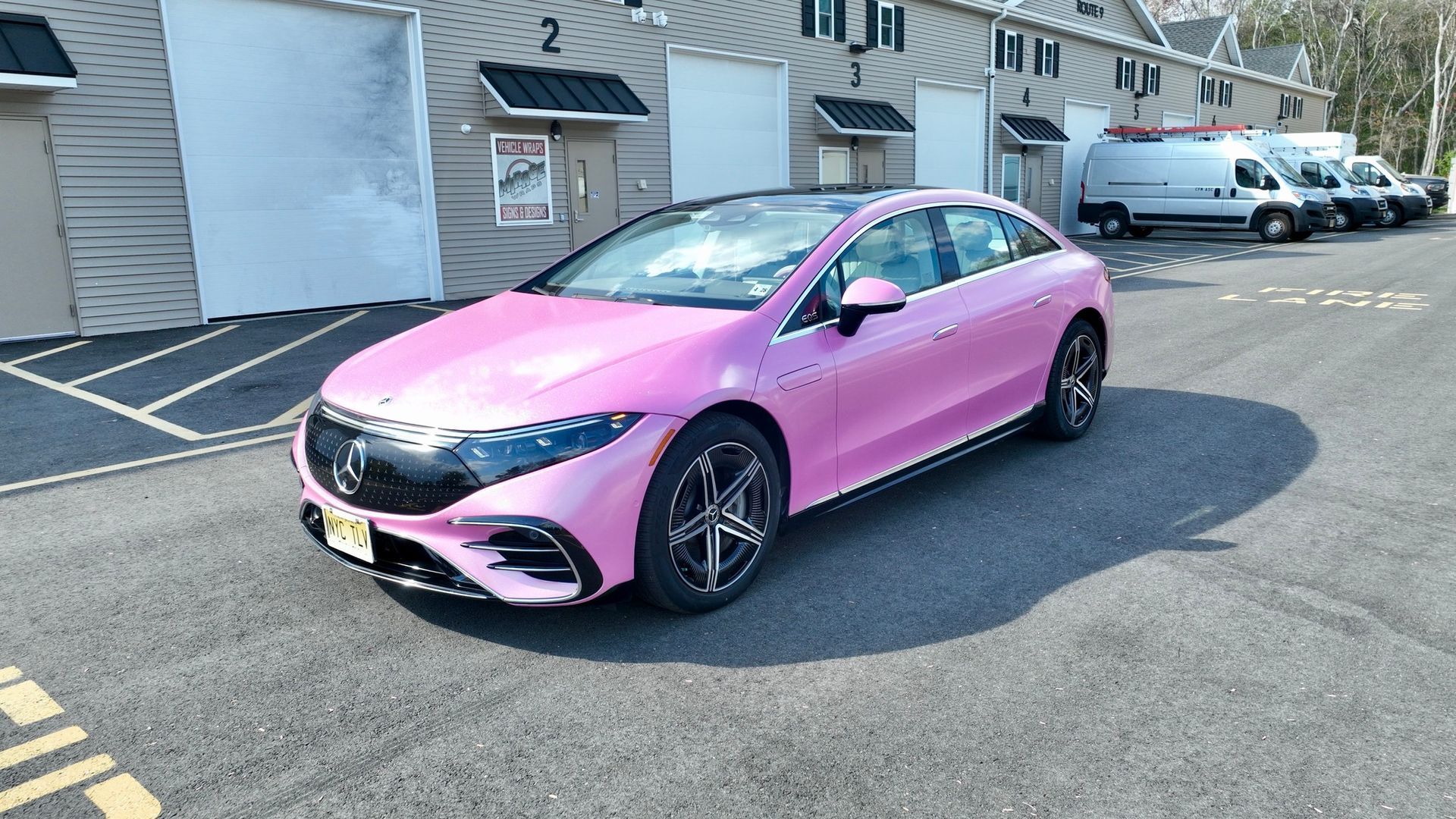 Pink sedan parked in a residential lot beside apartment buildings