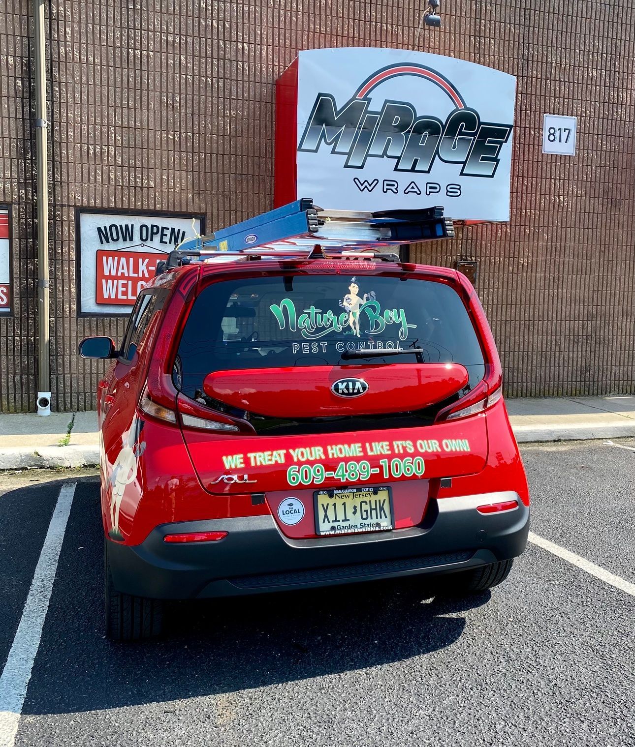 Red SUV with a roof sign parked in a lot in front of a brick wall and signs.