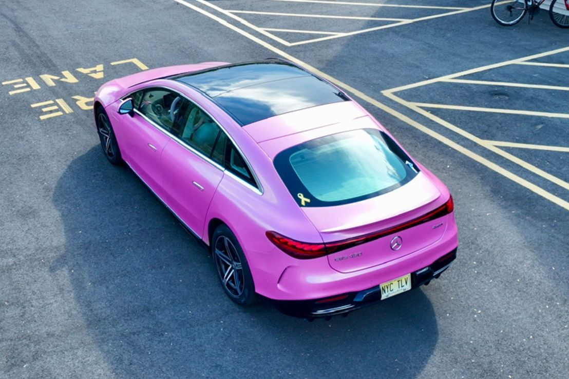 Pink sports car parked on an asphalt lot with yellow road markings