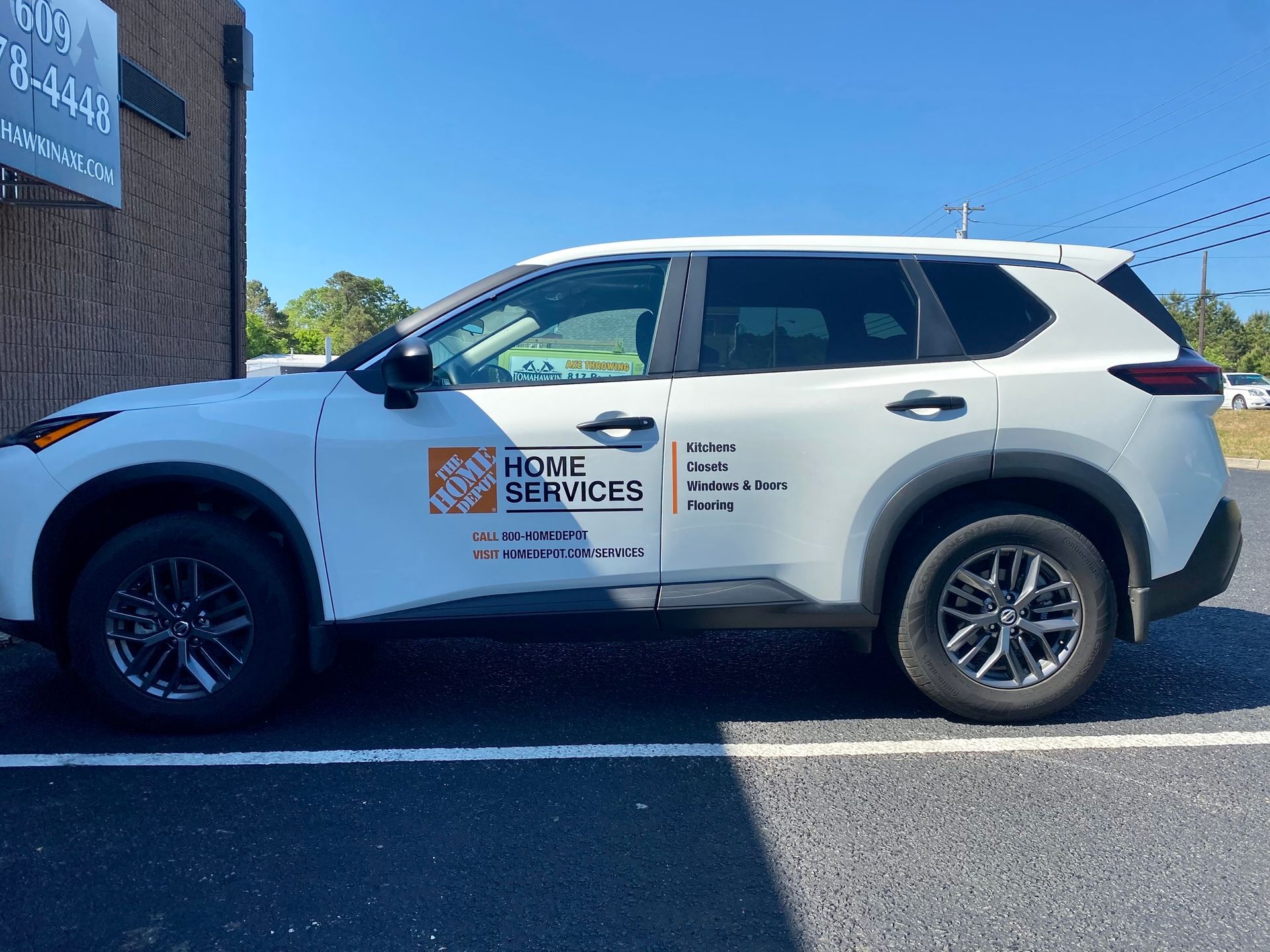 White roadside service SUV with company logo parked in a lot beside a building under a clear sky