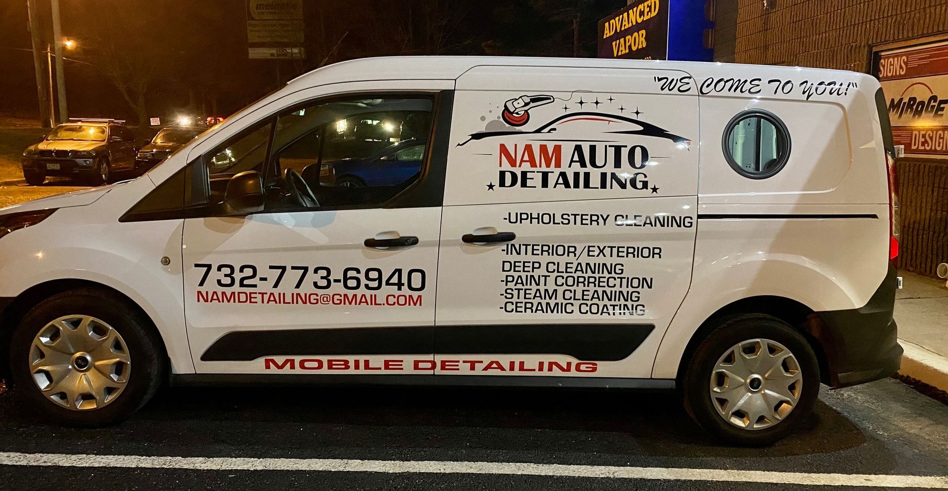 White mobile detailing van parked at night with large business signage on the side.