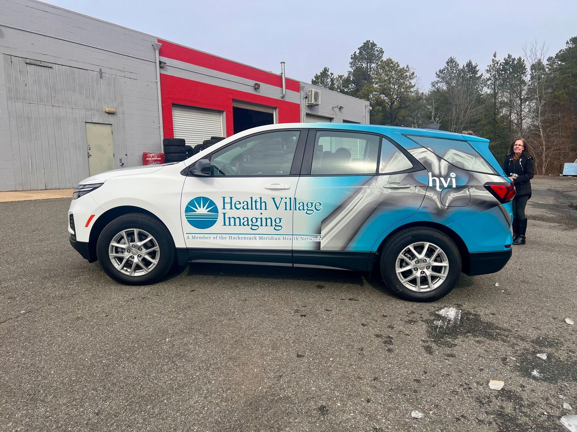 Blue Health Village Imaging SUV parked outside a building, with a person standing beside it.