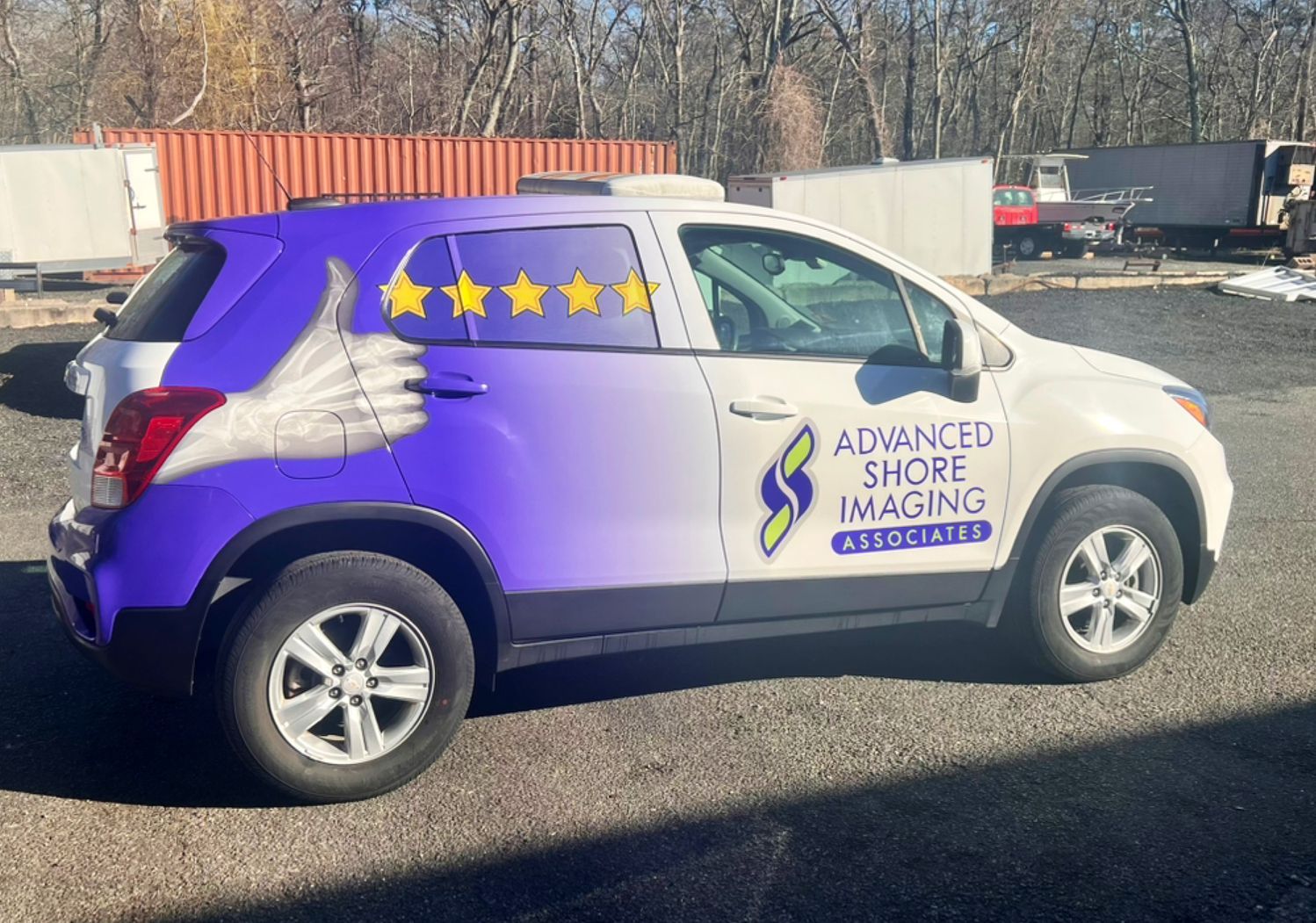 Purple-and-white Advance Shore Imaging car with wing graphics parked outdoors in a lot