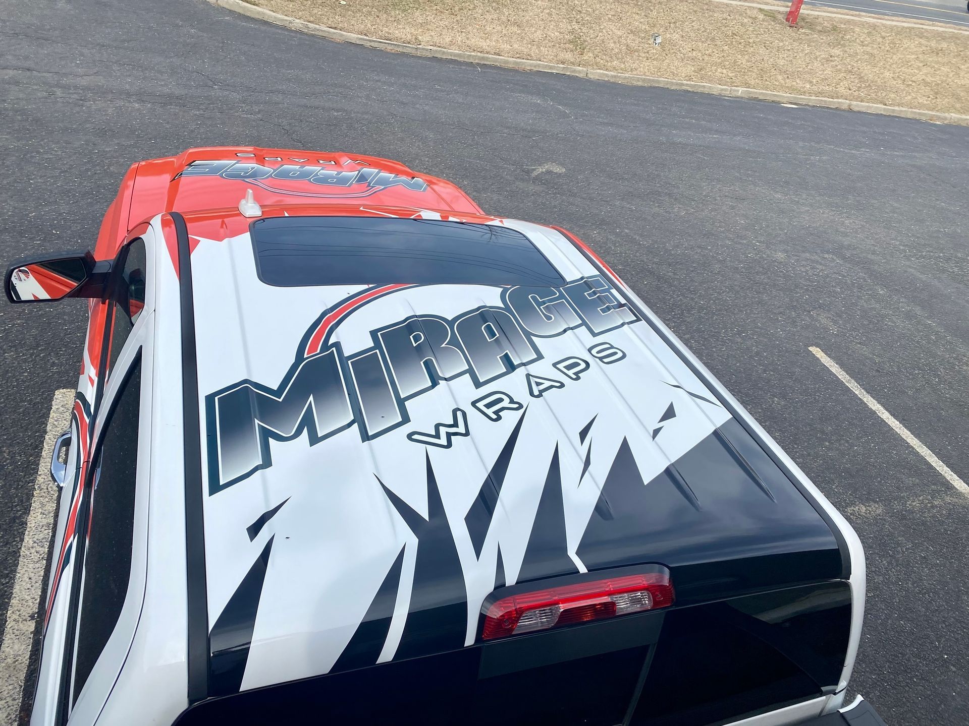 Overhead view of a white and red race car with a large graphic design on the roof.