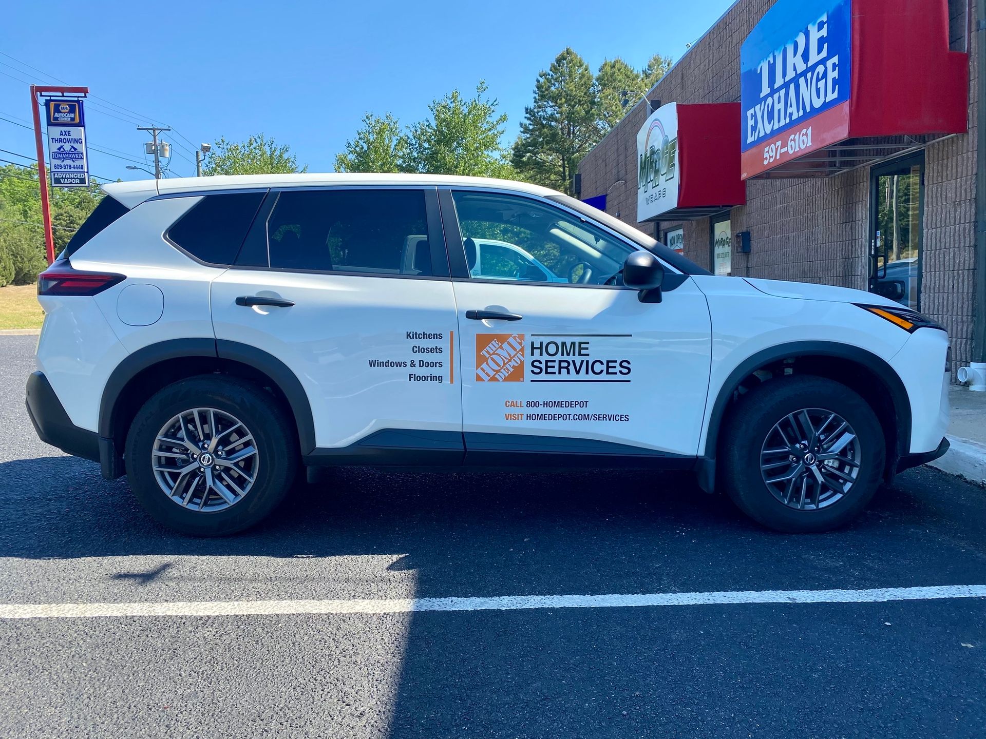 White SUV with company logo parked outside a Tire Choice shop on a sunny day