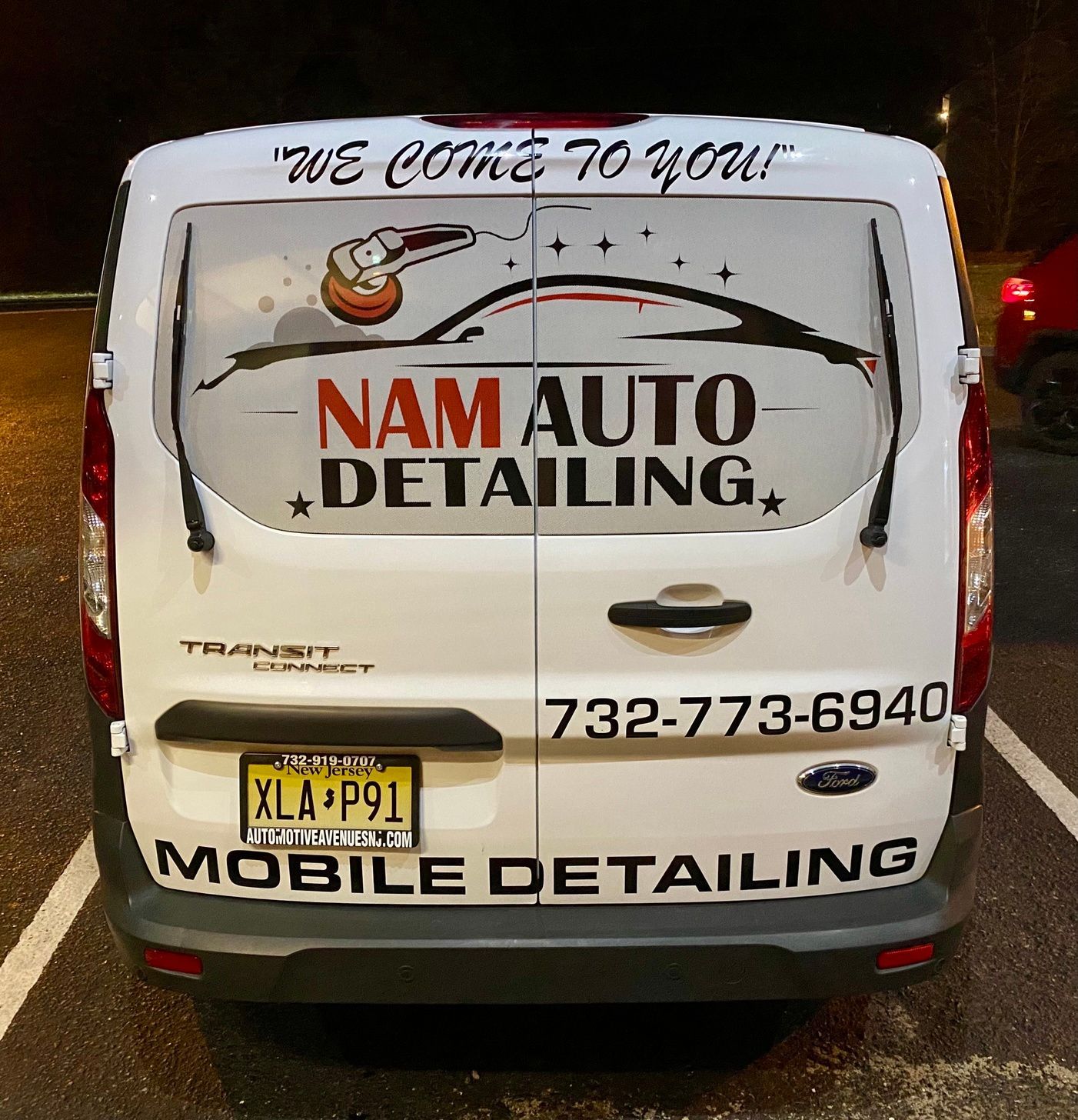 White van with “NAM AUTO DETAILING” and “MOBILE DETAILING” signage, phone number on back, parked at night