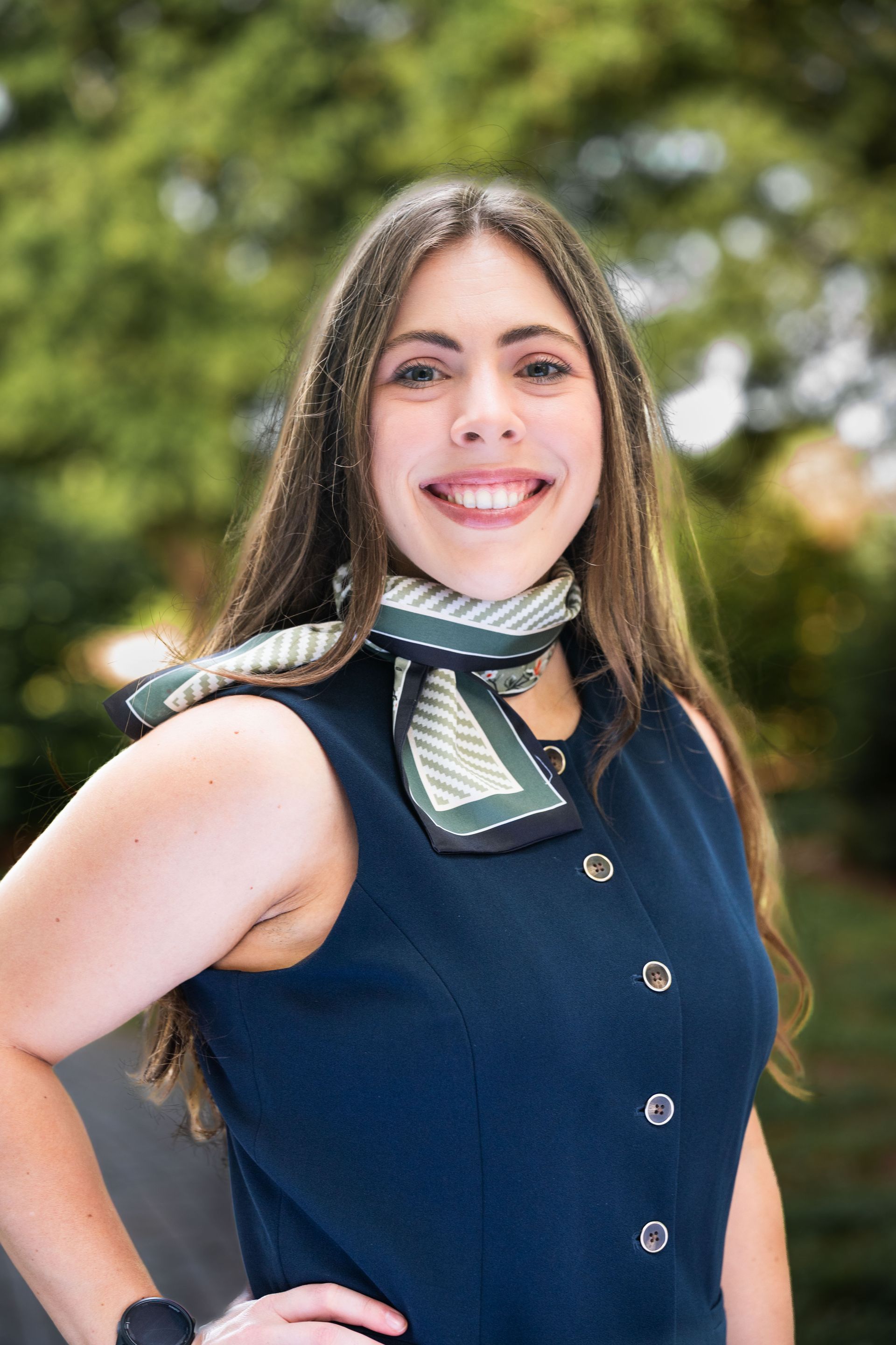 A woman wearing a scarf and a necklace is smiling for the camera.