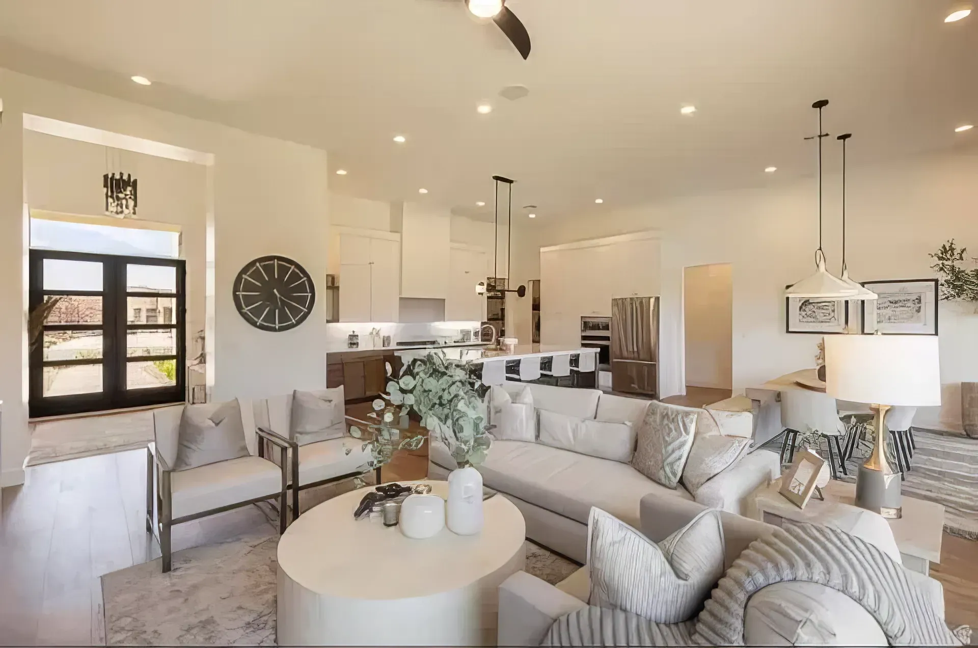 Bright modern living room with beige sofas, round coffee table, wall art, and large windows