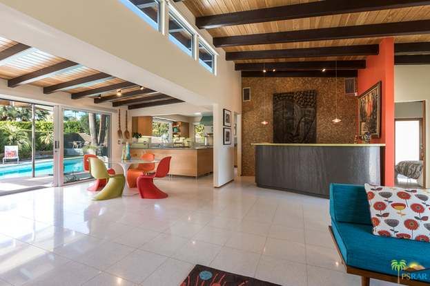 A living room with a couch , table , chairs and a counter.
