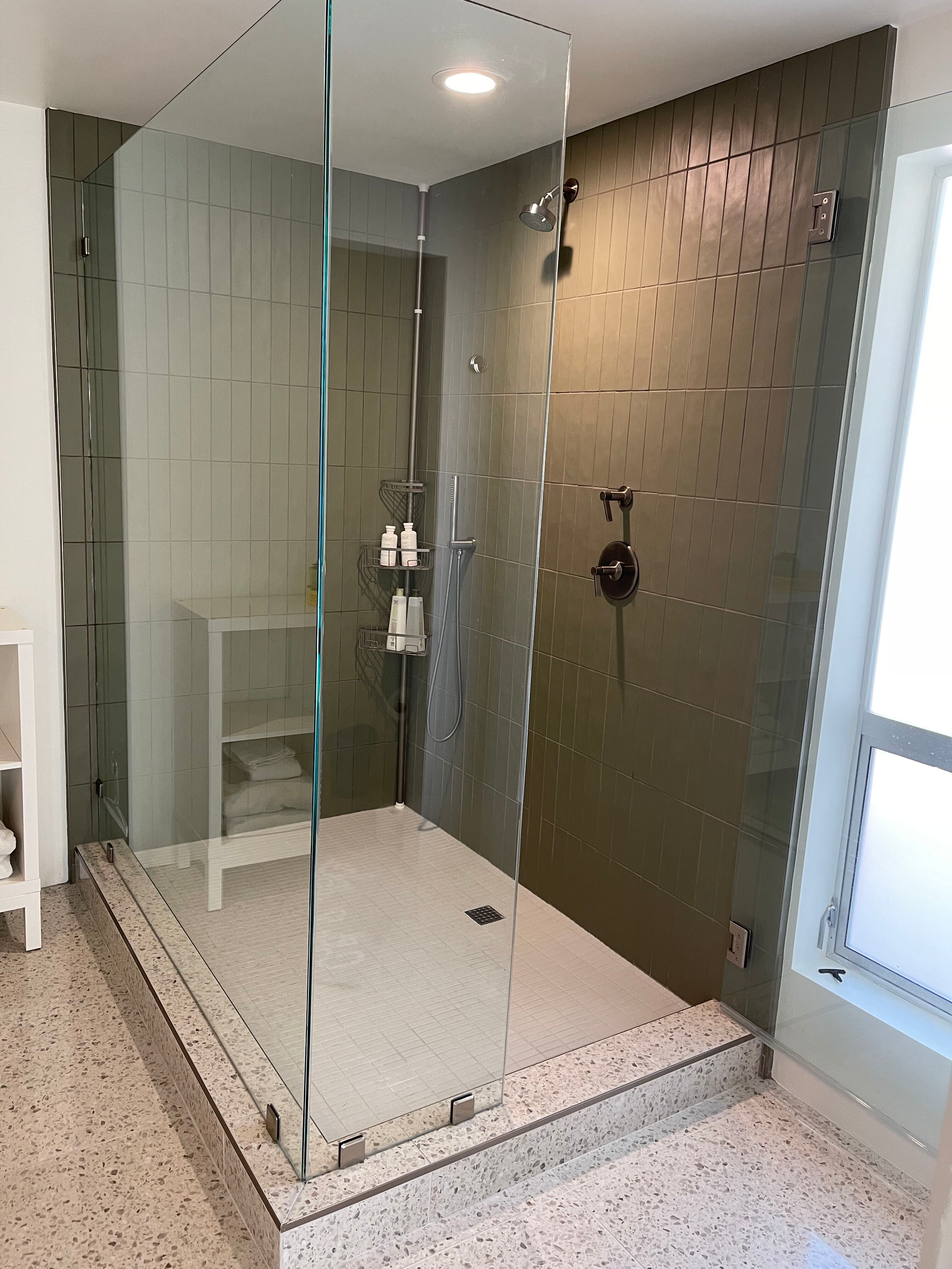 A bathroom with a walk in shower with a glass door.