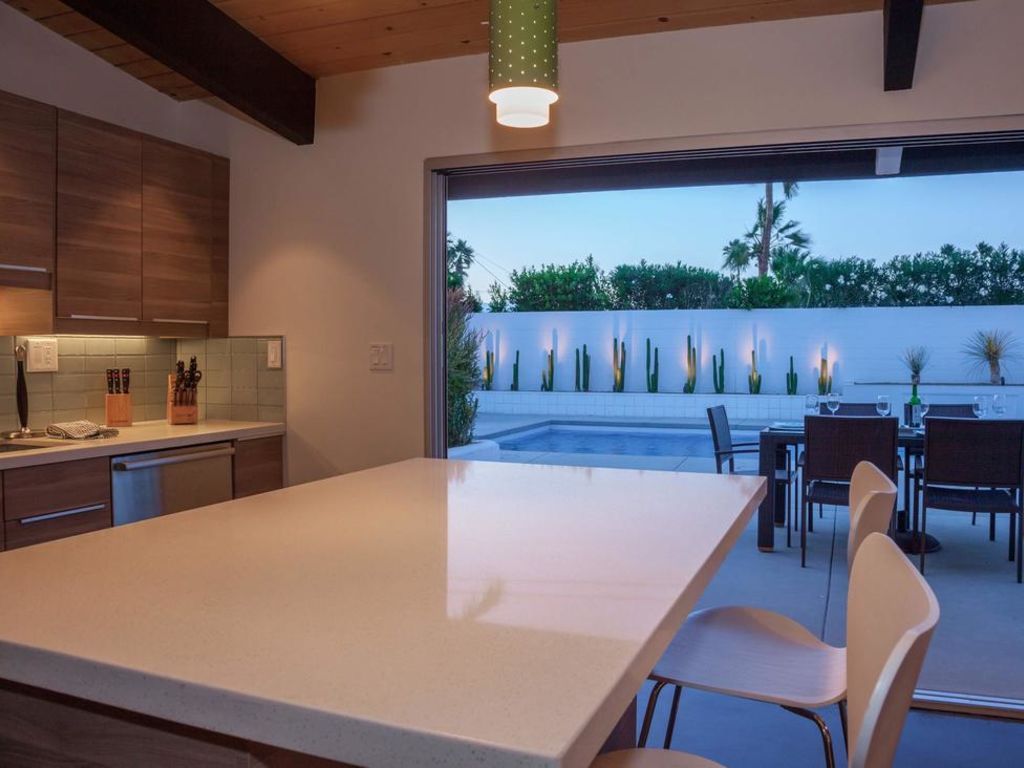 A kitchen with a table and chairs and a view of a pool