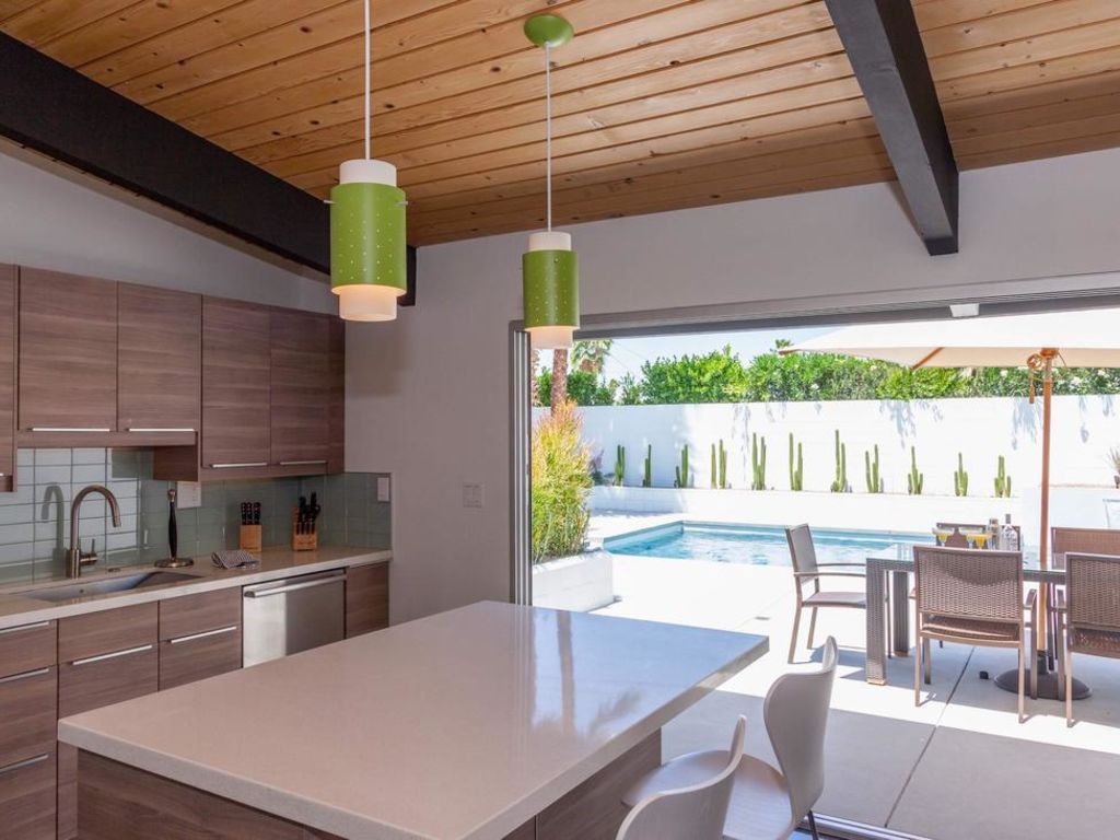 A kitchen with a table and chairs and a pool in the background
