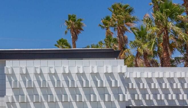 A building with a pattern on it and palm trees in the background.