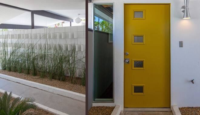 A yellow door with square windows is sitting next to a white wall.