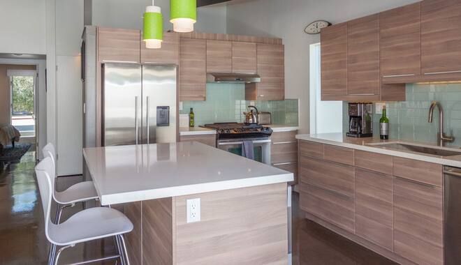 A kitchen with wooden cabinets , white counter tops , stainless steel appliances and a large island.