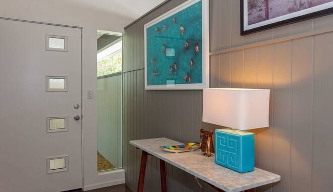 There is a table with a lamp on it in the hallway.