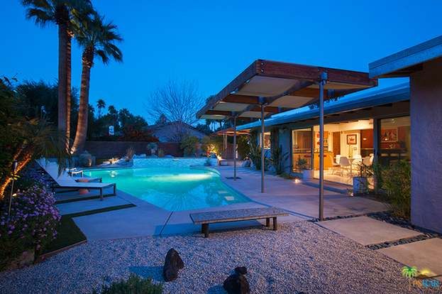 A house with a large swimming pool in front of it