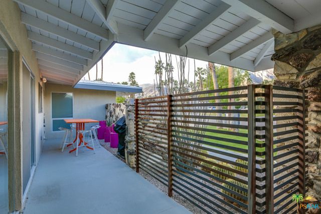 A patio with a wooden fence and a table and chairs.