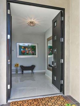 A black door is open to a hallway with a painting on the wall.