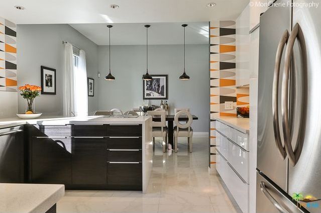 A kitchen with black cabinets and a stainless steel refrigerator
