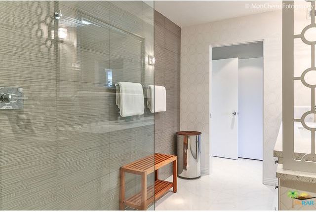 A bathroom with a walk in shower and a wooden bench