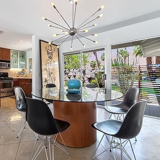 A dining room with a glass table and chairs and a chandelier.