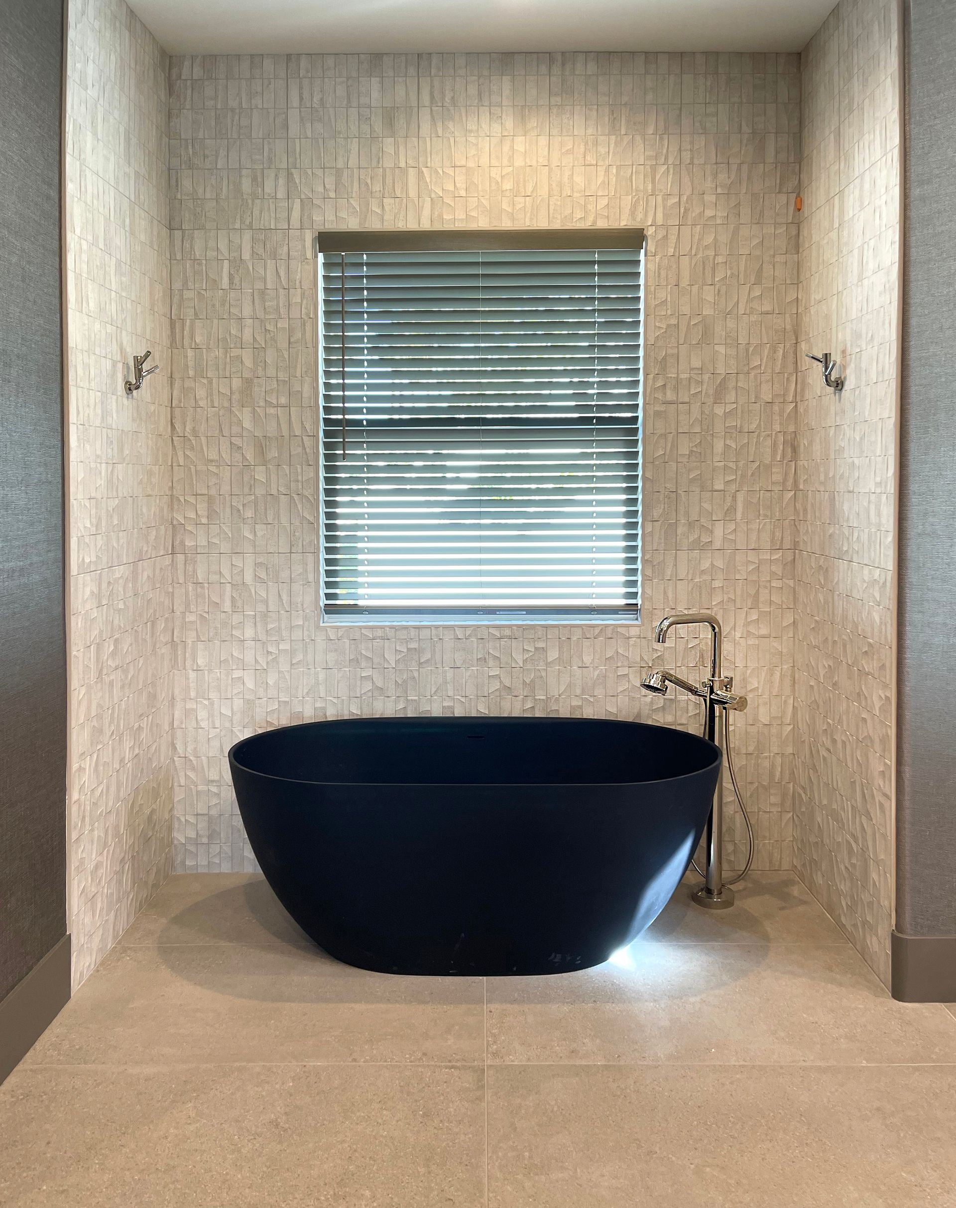 A black bathtub is sitting in a bathroom next to a window.