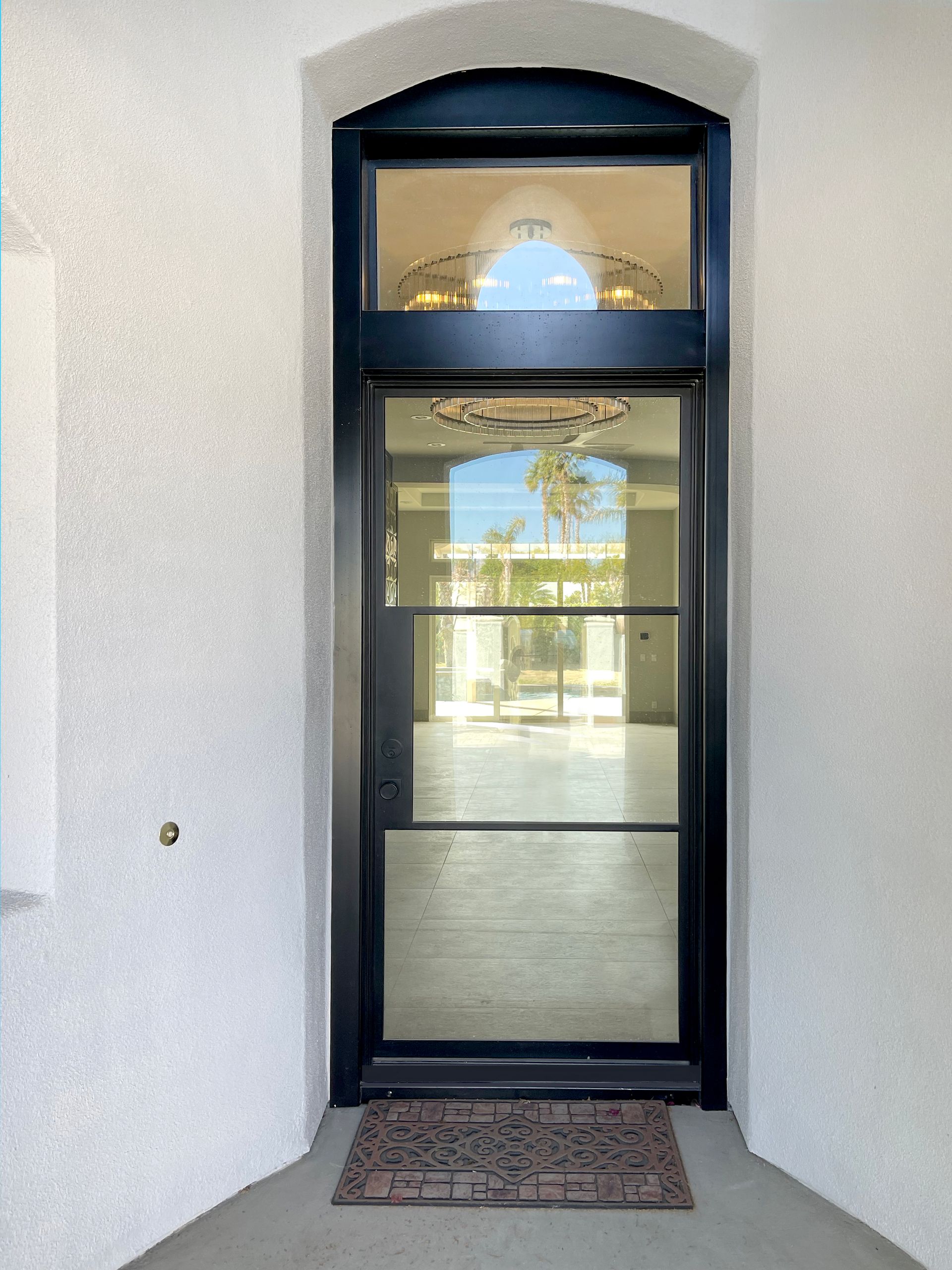 A black door with a window and a rug on the floor