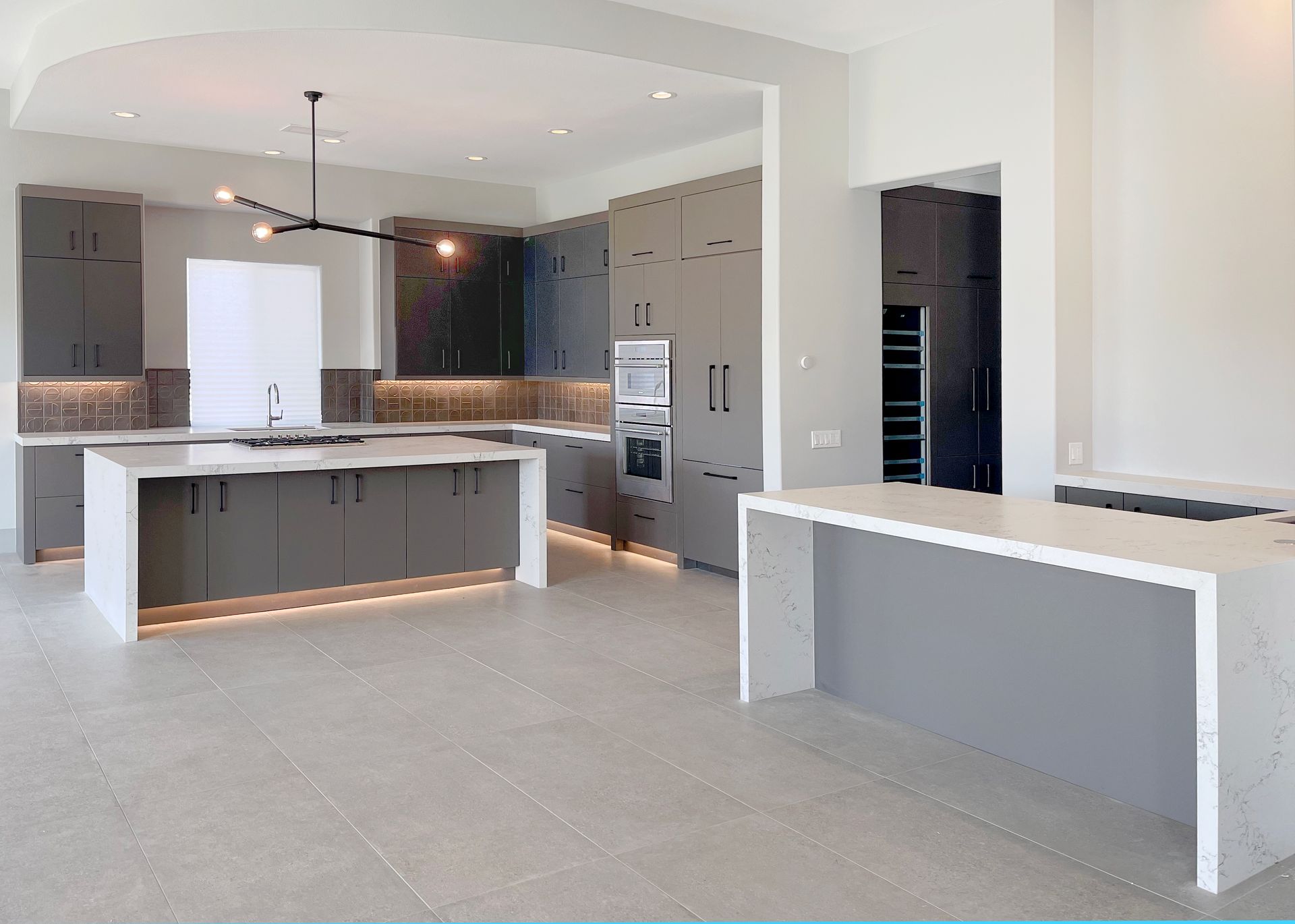 An empty kitchen with gray cabinets and white counter tops