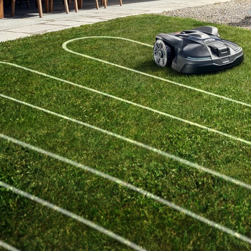 A Robotic Lawn Mower Is Cutting A Lush Green Lawn — Mid Coast Mowers In Taree, NSW