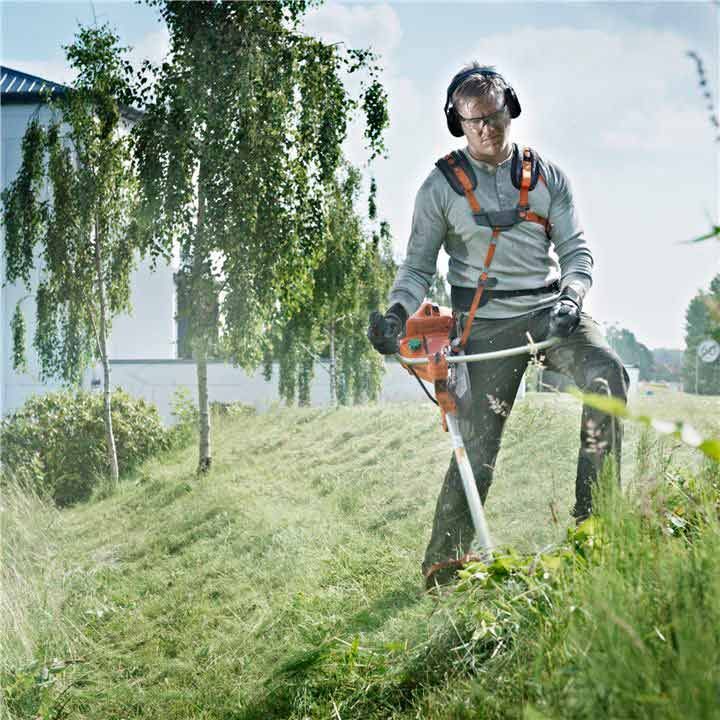 A Man Is Cutting Grass With A Lawn Mower In A Field — Mid Coast Mowers In Taree, NSW