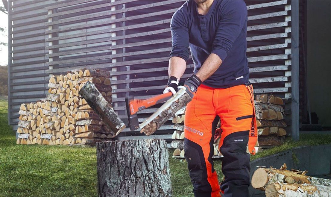 A Man Chopping Down Logs With An Axe — Mid Coast Mowers In Taree, NSW