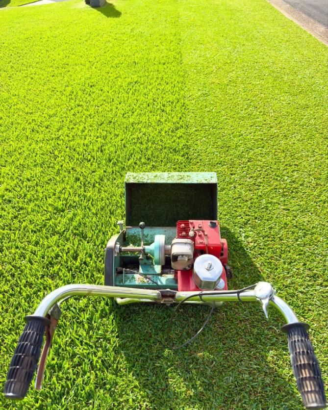 A well-manicured green lawn with lawnmower — Mow & Mulch Lawn & Garden Maintenance In Salamander Bay, NSW